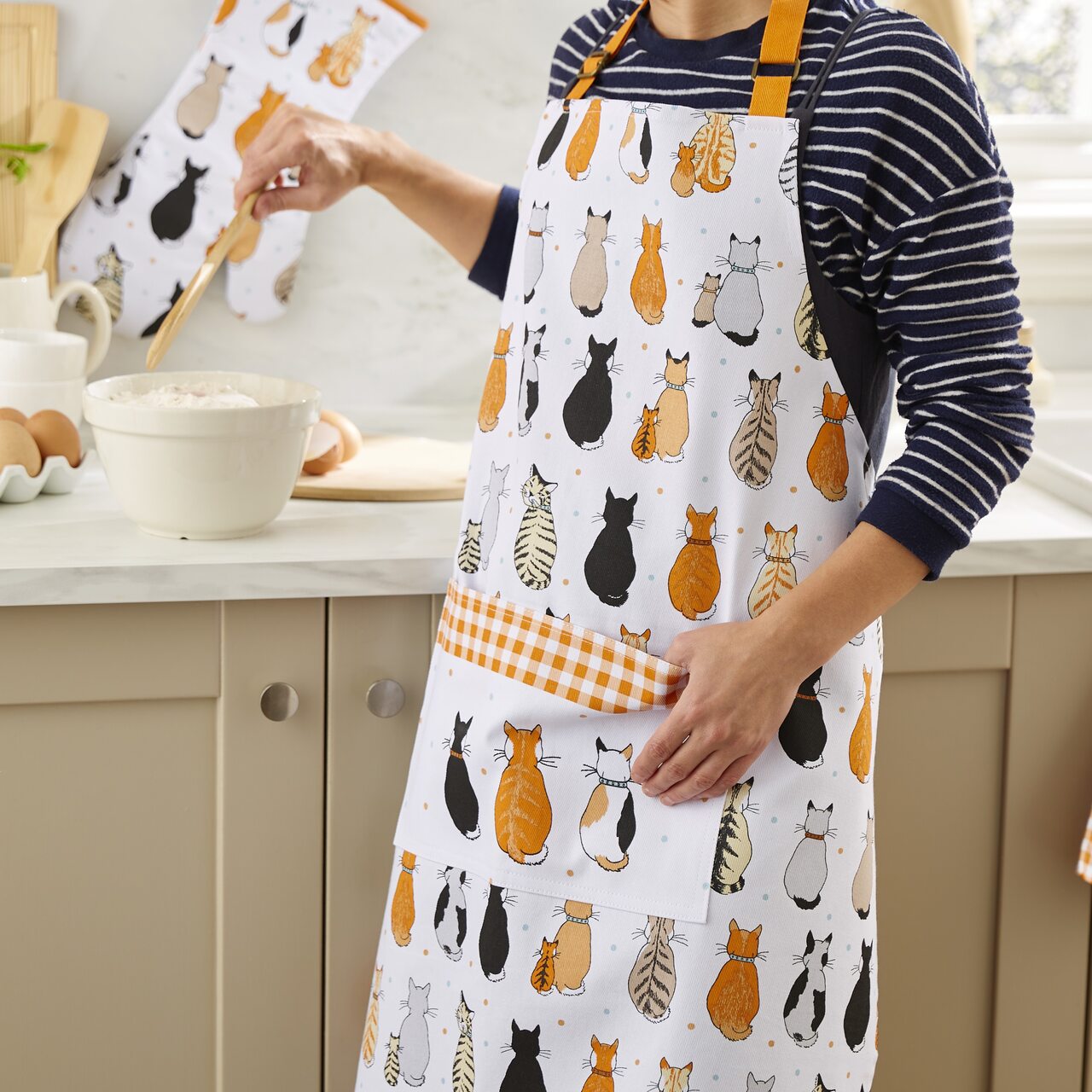 Baumwollschürze "Wartende Katzen" mit orangefarbenem Nackenband und Landhaus-Karos am Rand der großen vorne angebrachten Tasche, von Ulster Weavers, aus England