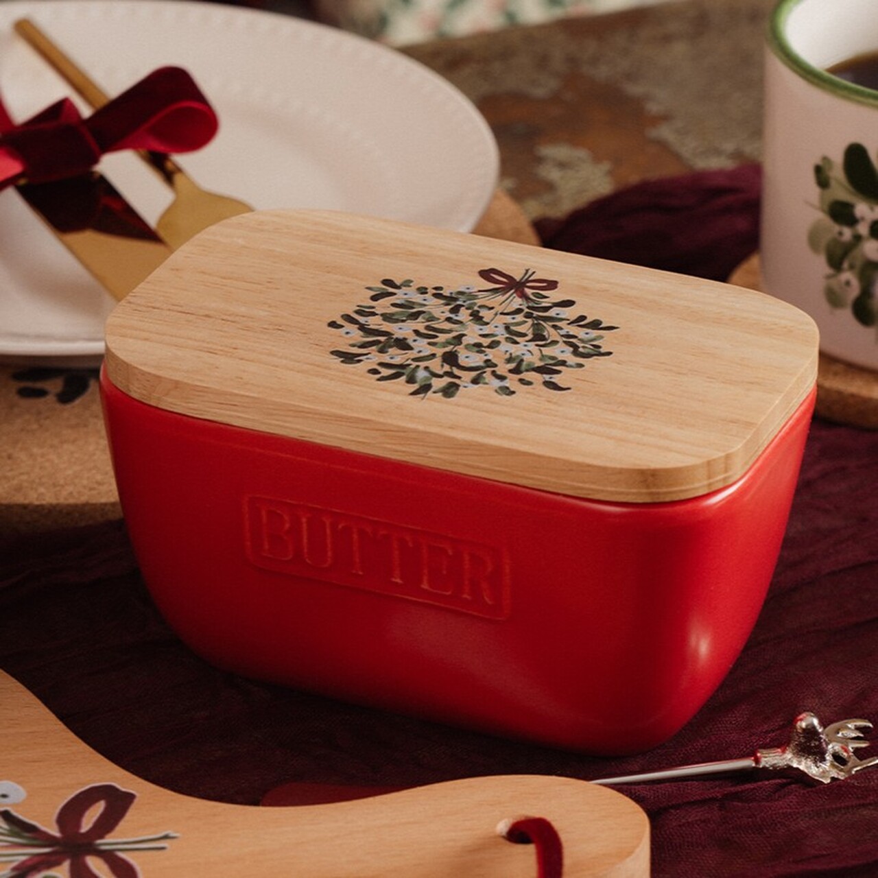 Rote Keramik-Butterdose mit Mistelmotiv auf dem Holzdeckel - Mistelzweige mit weißen Beeren, mit einer roten Schleife zusammengebunden | Weihnachtliche Dekoration für den Frühstückstisch